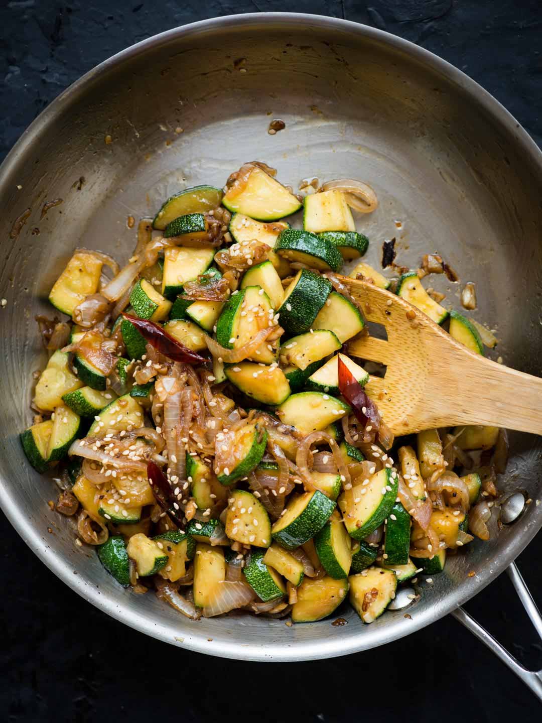 Zucchini stir fried in a metal pan.