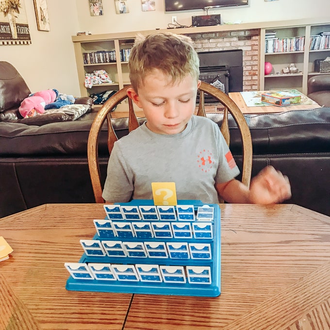 A boy playing guess who.