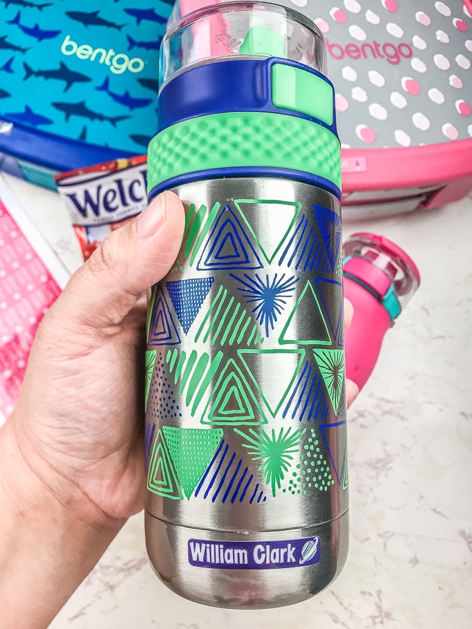 A hand holding a blue and green stainless steel water bottle.
