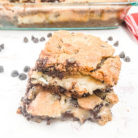 Two chocolate chip cookie cheesecake bars stacked up.