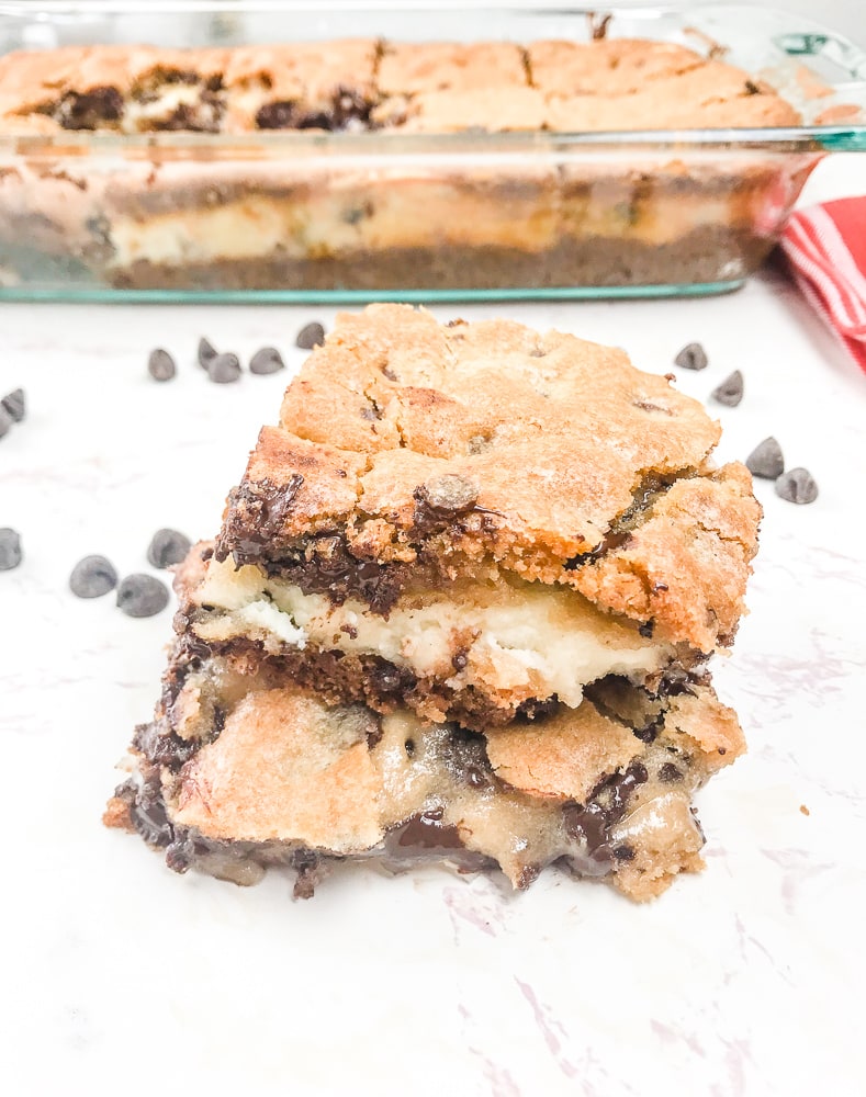 Two chocolate chip cookie cheesecake bars stacked up.