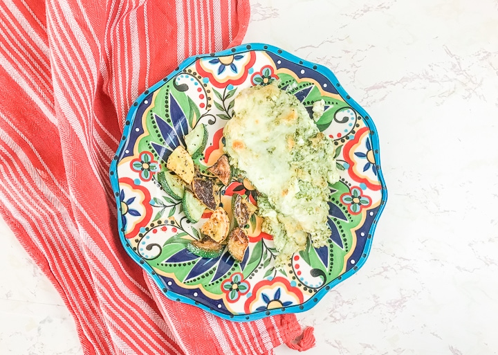 A red striped tea towel under a plate of creamy pesto chicken.