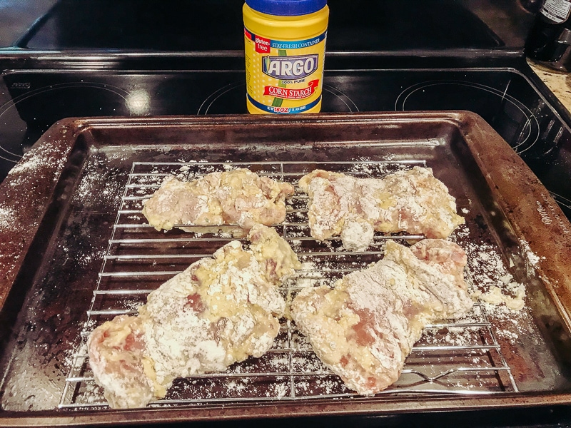 Coated chicken thighs on a rack.