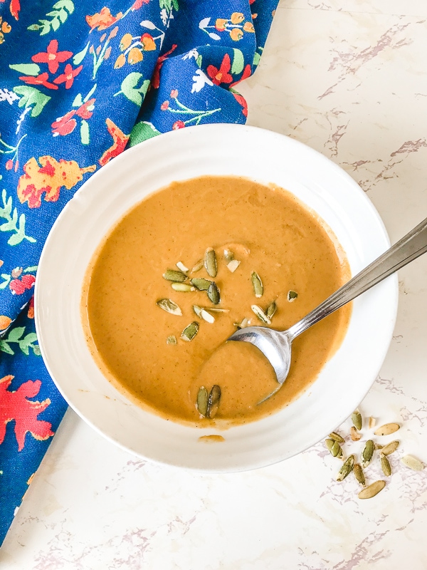 A bowl of easy pumpkin soup with a spoon sticking out of the bowl.
