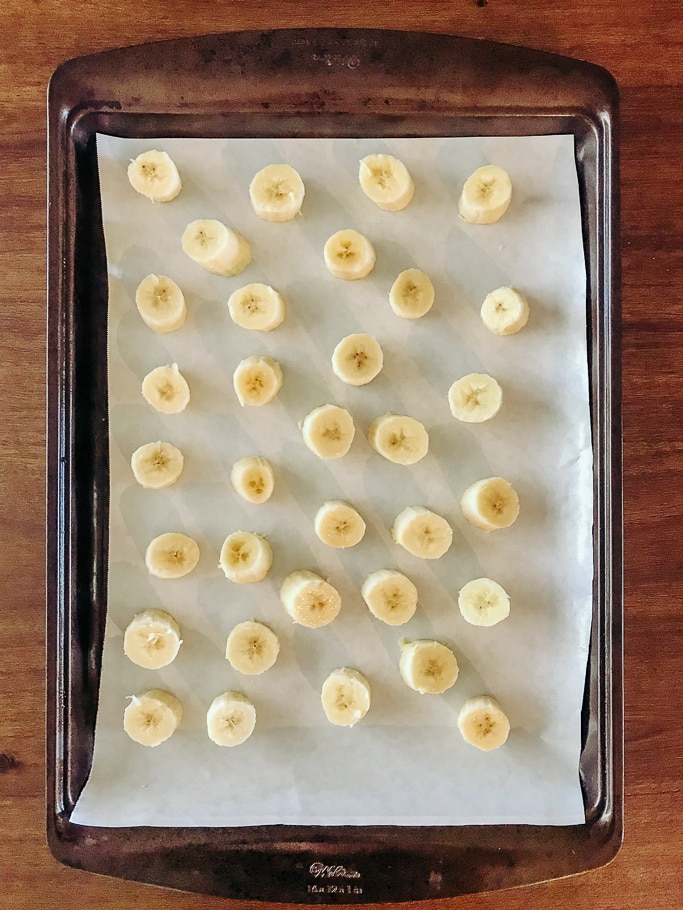 A cookie sheet with sliced bananas showing how to freeze bananas.