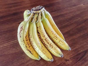 A picture of a bunch of bananas on a wooden table.
