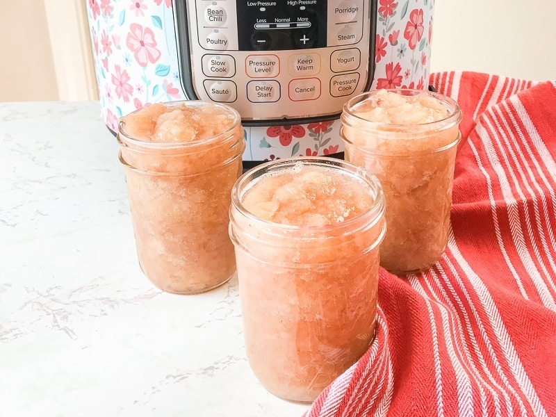 Three jars of instant pot applesauce next to a red striped towel.