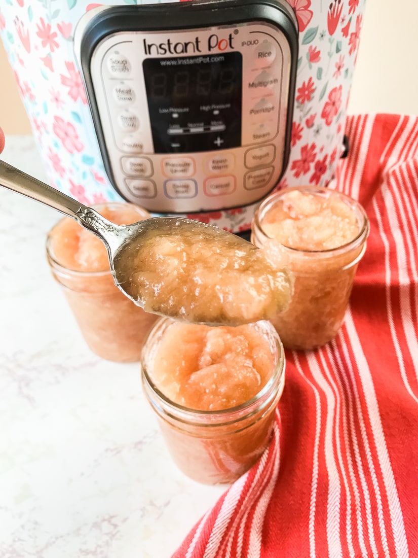 A spoon holding up a bite of instant pot applesauce.