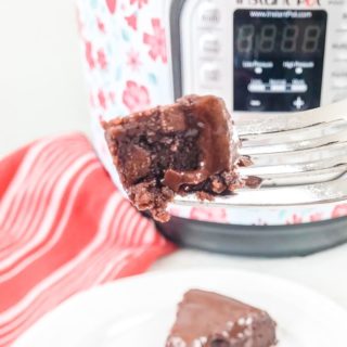 A bite of instant pot brownies held up on a fork in front of an instant pot.