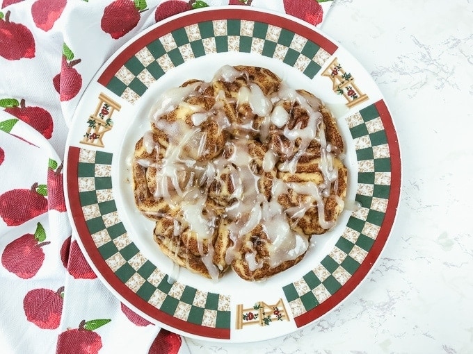 A red and green fall-themed plate topped with instant pot pillsbury cinnamon rolls.