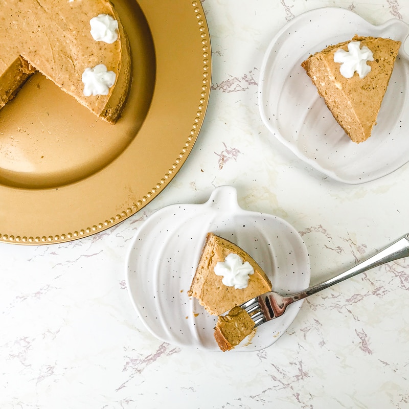 Two pumpkin shaped plates with slices of instant pot pumpkin cheesecake.