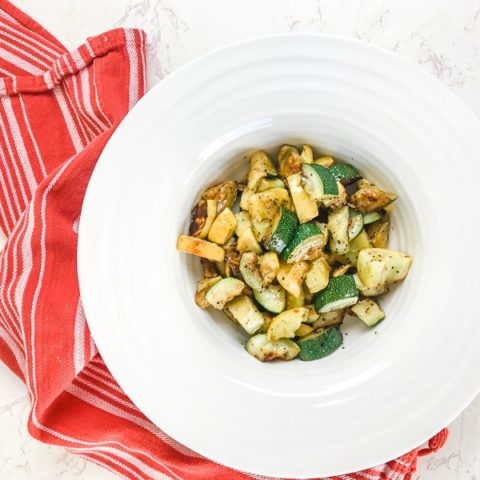 A white bowl filled with roasted zucchini and yellow squash.
