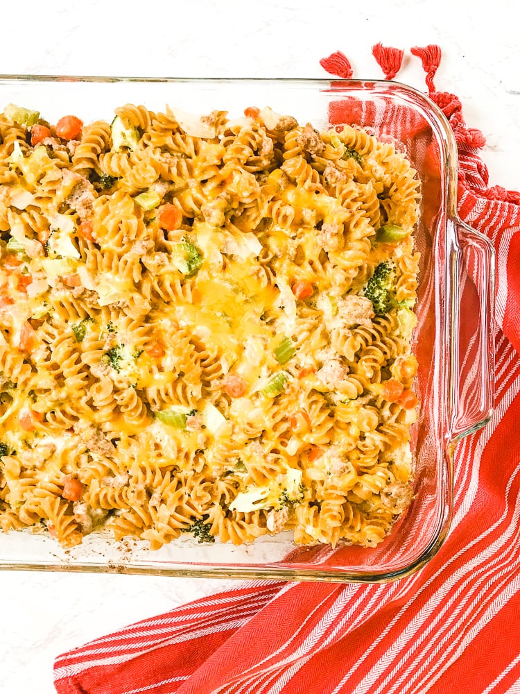 A casserole dish of leftover turkey casserole next to a red striped towel.