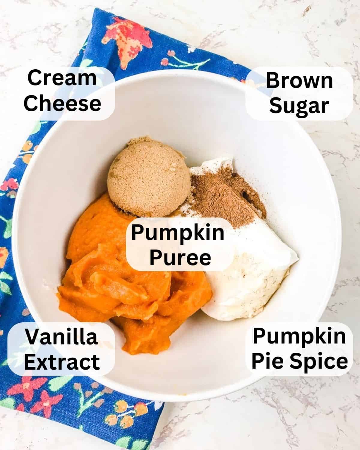 A white ceramic bowl filled with ingredients to make pumpkin dip.