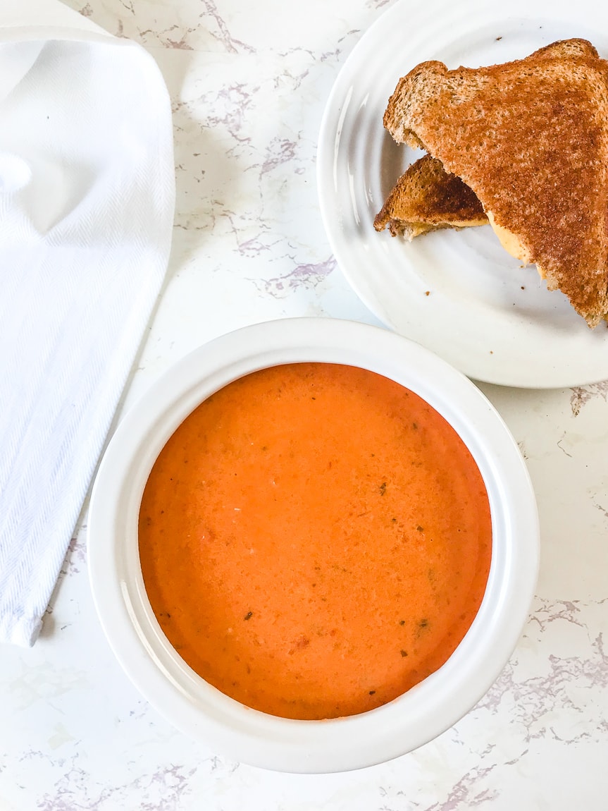 A white bowl filled with the homemade creamy tomato basil soup recipe.