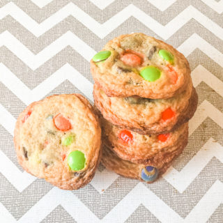 A stack of halloween cookies made with chocolate chips and orange and green M&Ms.