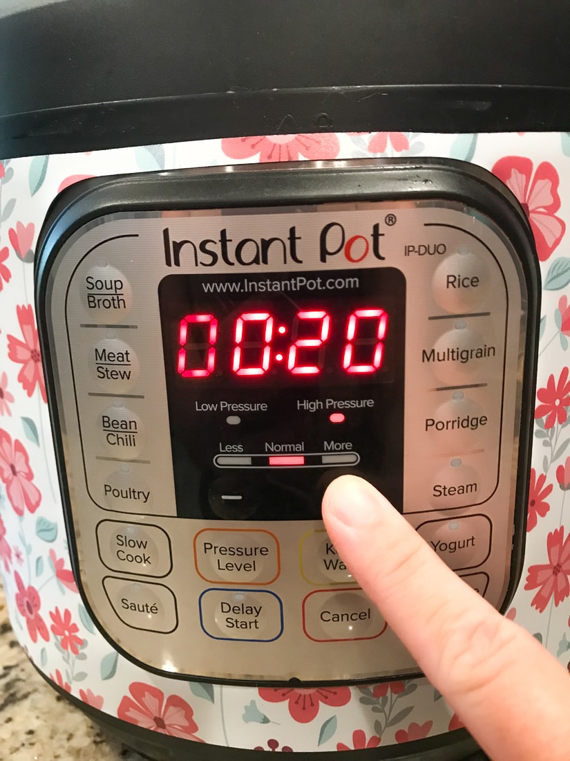 A finger setting the instant pot to 20 minutes.