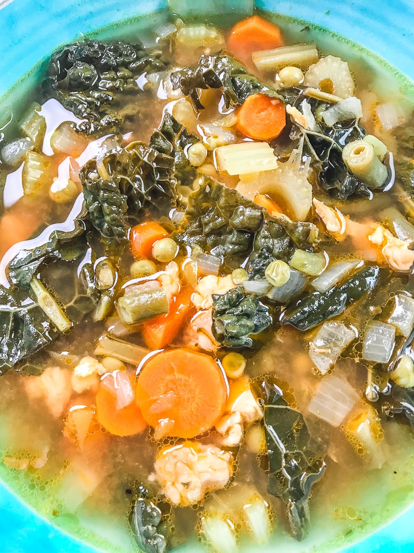 Close up of pressure cooker chicken vegetable soup showing the kale, carrots, peas, and chicken.