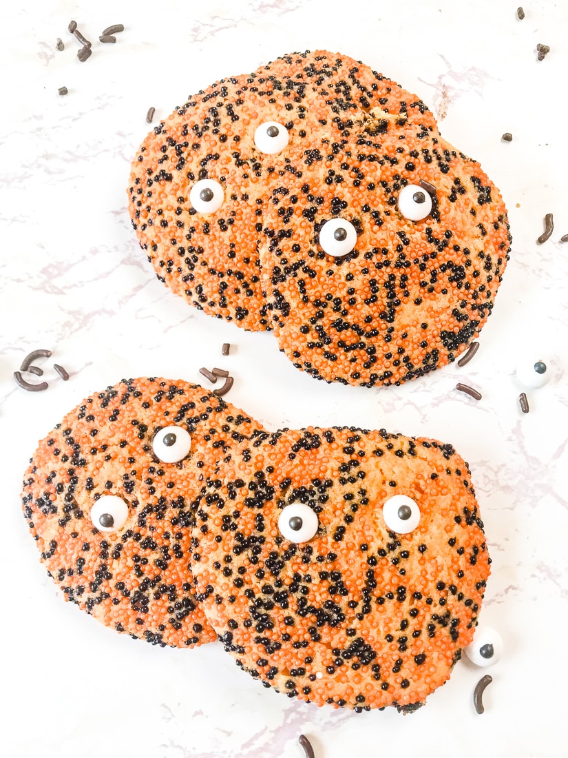 Two stacks of halloween sprinkle cookies with candy eyes.