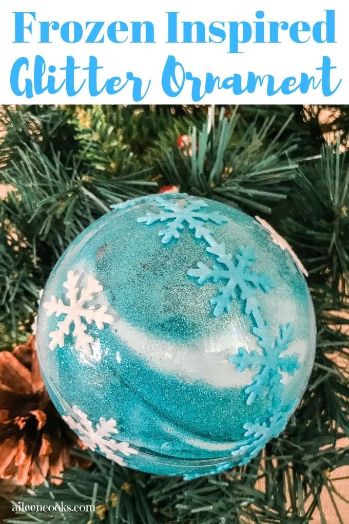 A blue frozen inspired ornament hanging from a tree.