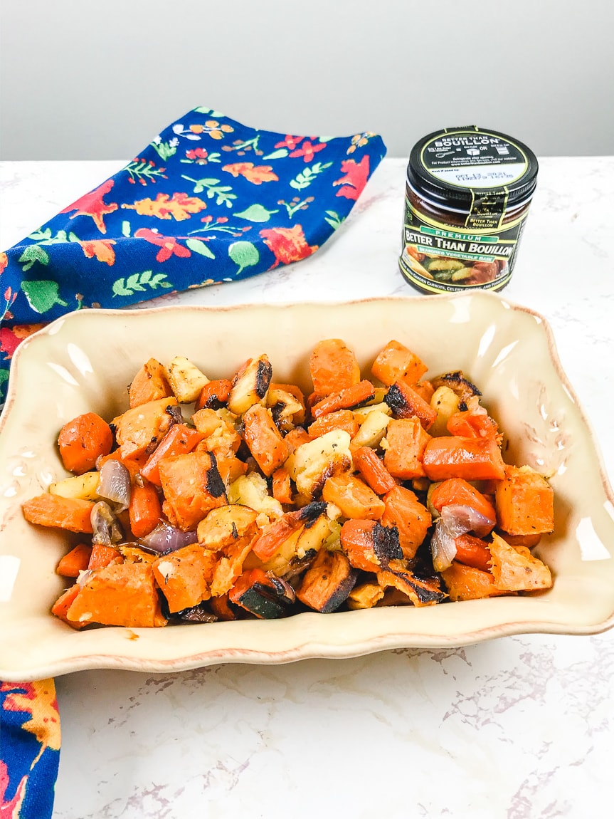 A baking dish filled with roasted root vegetables next to a jar of Better Than Bouillon.