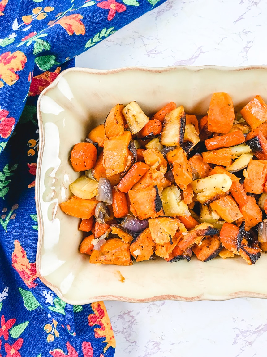 Roasted root vegetables in a baking dish including sweet potato, parsnips, and carrots.