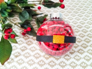 Santa belt ornament on display in front of a branch of holy.