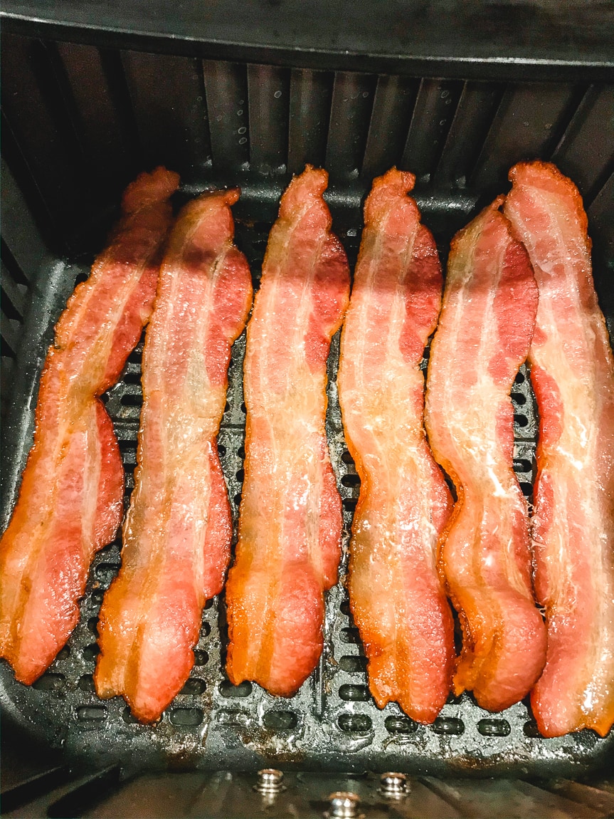 Perfectly crisp air fryer bacon inside basket of air fryer.
