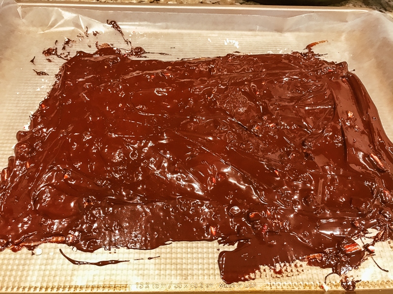Melted semi sweet chocolate spread over crushed candy canes on a cookie sheet.