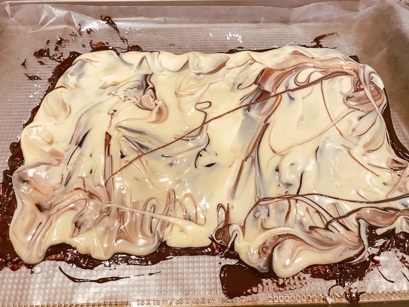 White chocolate spread over melted semi sweet chocolate on a cookie sheet.