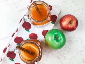Overhead shot of two glasses of instant pot apple cider next to a red and green apple.