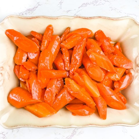 A cream colored serving dish filled with instant pot carrots.