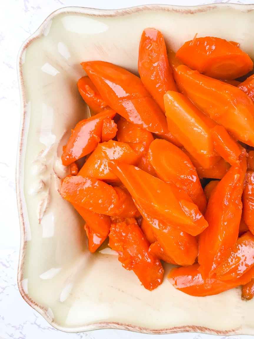 A side view of instant pot carrots in a cream colored serving dish.