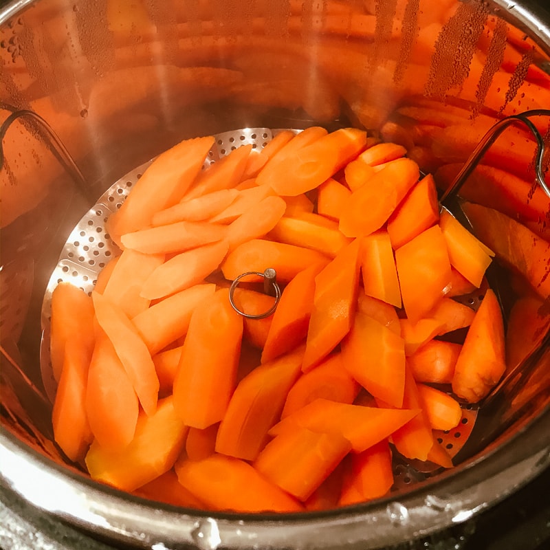 Peeled and cut carrots in a steamer basket inside of the instant pot.