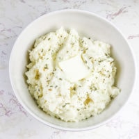 A bowl of Keto cauliflower mashed potatoes with a slice of butter on top.