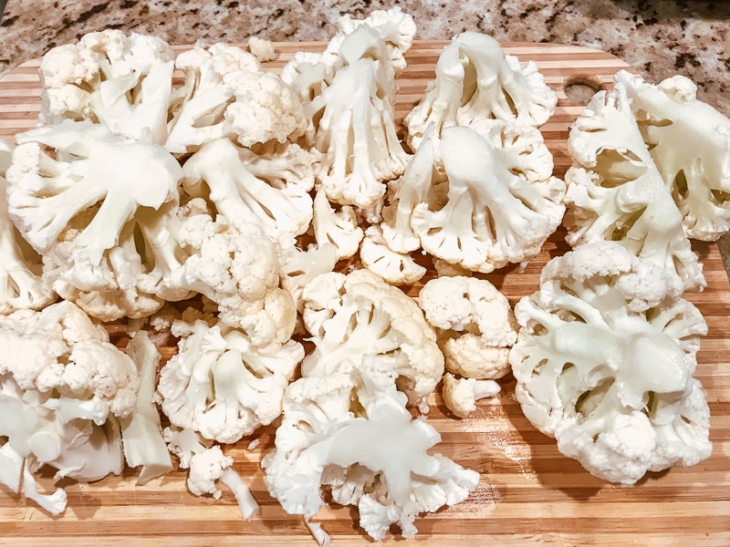 A cutting board filled with cauliflower florets.