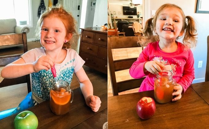 Two girls sitting at a table smiling and drinking instant pot apple cider.