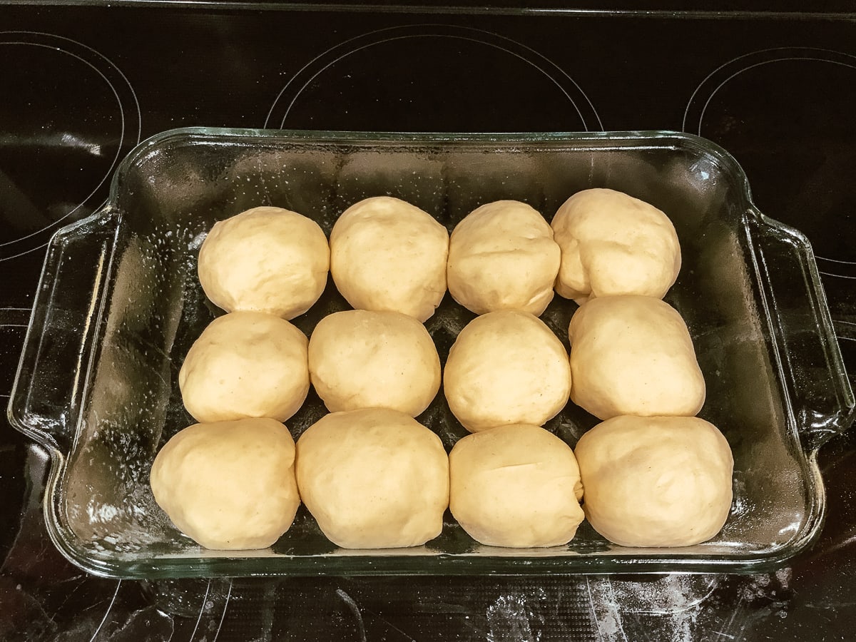 Parker house rolls dough after it has risen, dough balls are twice as big and now touching each other.