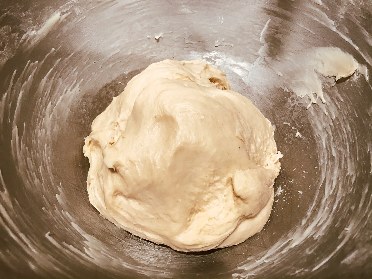 A smooth ball of dough in a metal bowl.