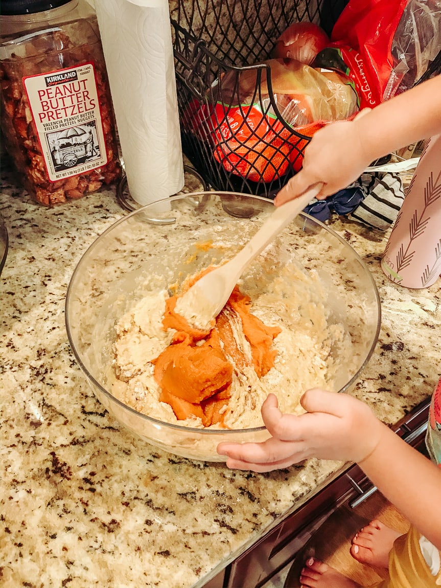 Little hands mixing pumpkin puree into the pumpkin cornbread batter.