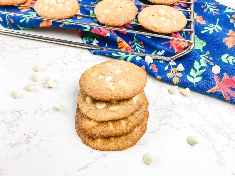 A cooling rack of cookies next to a stack of salted caramel cookies.