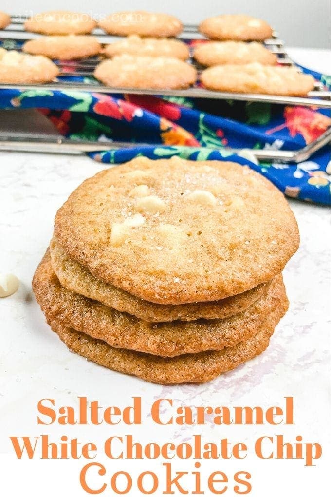 A stack of salted caramel cookies with cookies cooling on the rack in the background and the words "salted caramel white chocolate chip cookies"