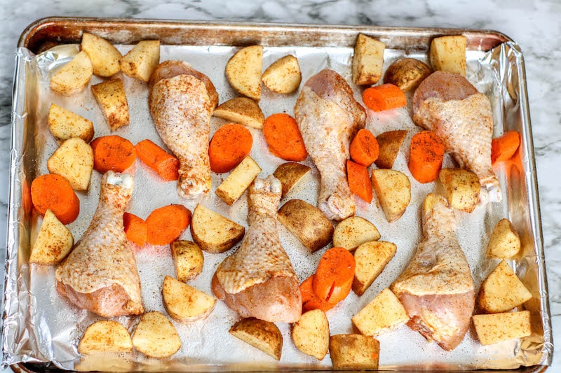 Chicken, potatoes, and drumsticks on a sheet pan.