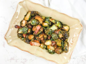 A rectangular serving dish filled with Brussels sprouts and bacon.