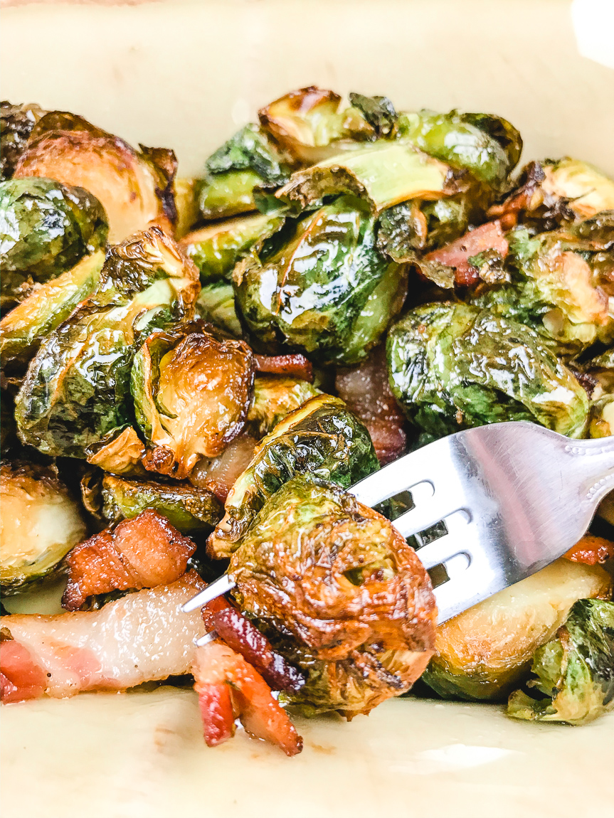 A fork holding air fried Brussels sprouts and bacon.