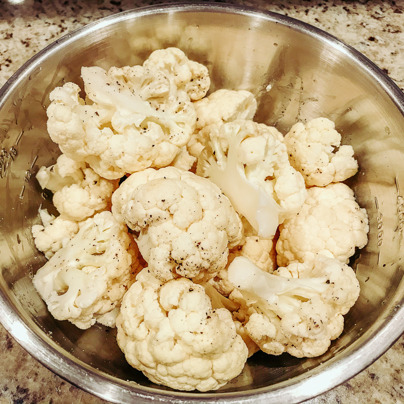 Bowl of cauliflower drizzled with oil.