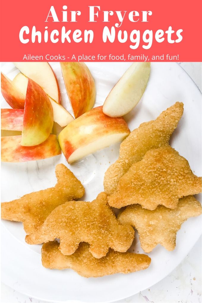 A plate of Dino chicken nuggets and apples with words "air fryer chicken nuggets" in red.