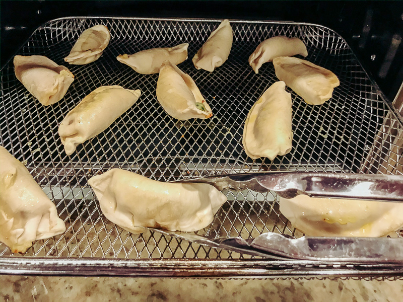Pot stickers being flipped in air fryer.