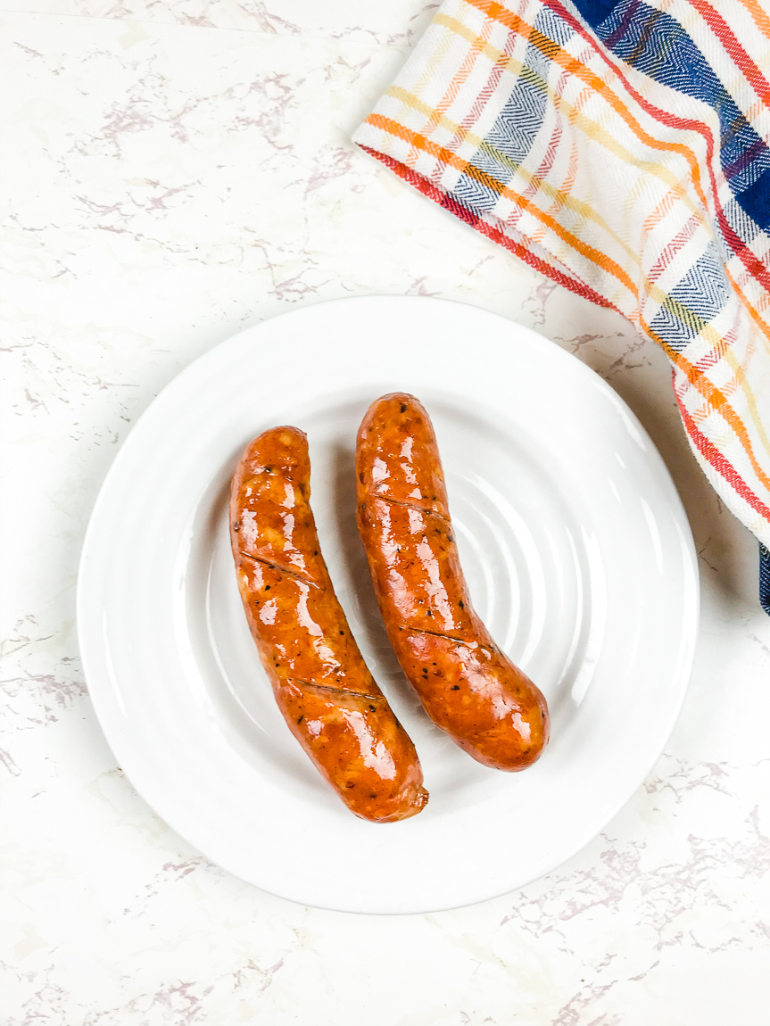 A plate of cooked sausages next to a striped towel.