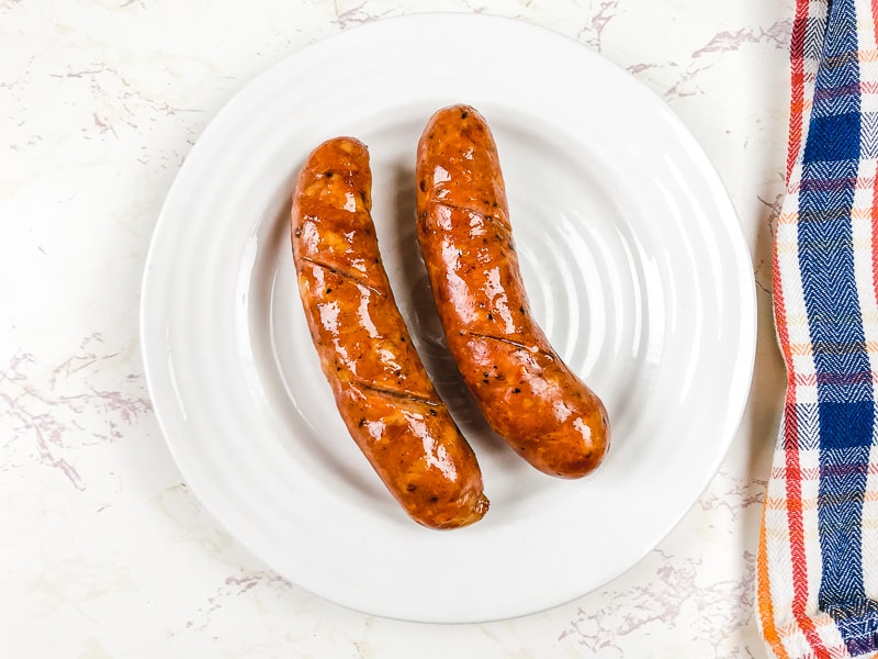 A white plate with two air fried sausage.